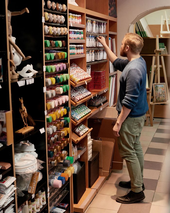 Business loans for small business: an art supply shop owner restocking paint on the shelves