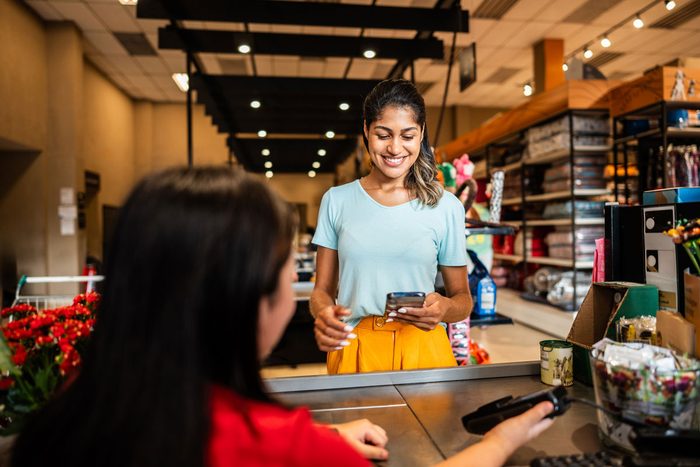 A shop owner serving a customer at the checkout counter