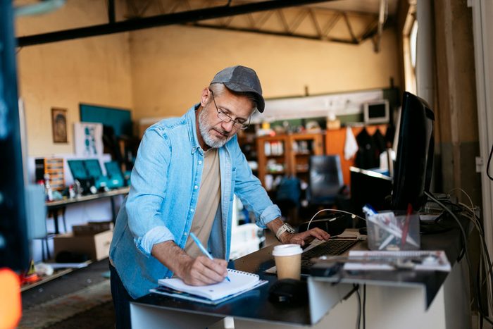 A shop owner making notes in a notebook at his counter