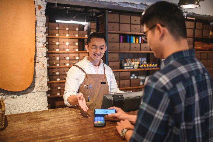 A shop owner taking a contactless payment across the counter