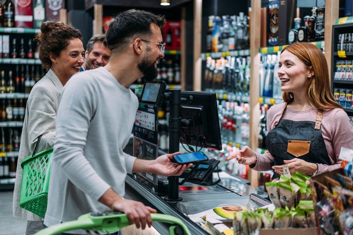 Customers paying by phone at a busy shop counter