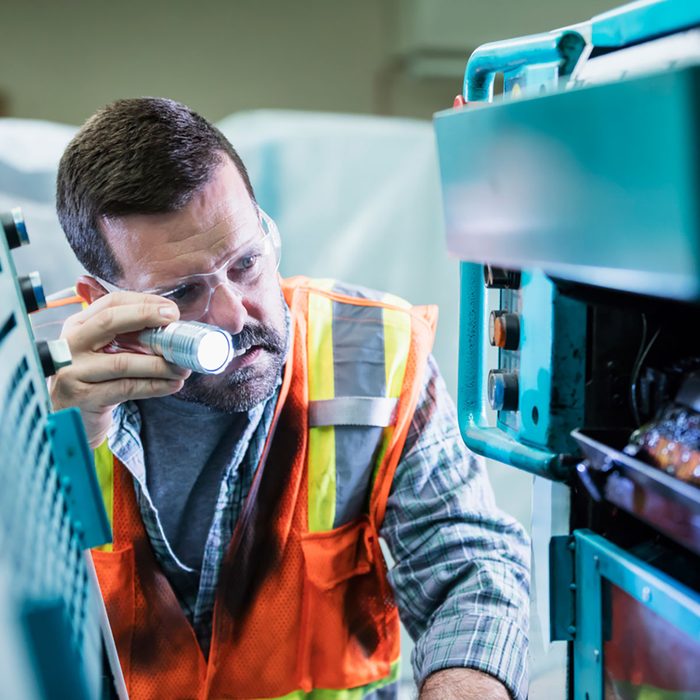 A technician inspecting equipment with a flashlight