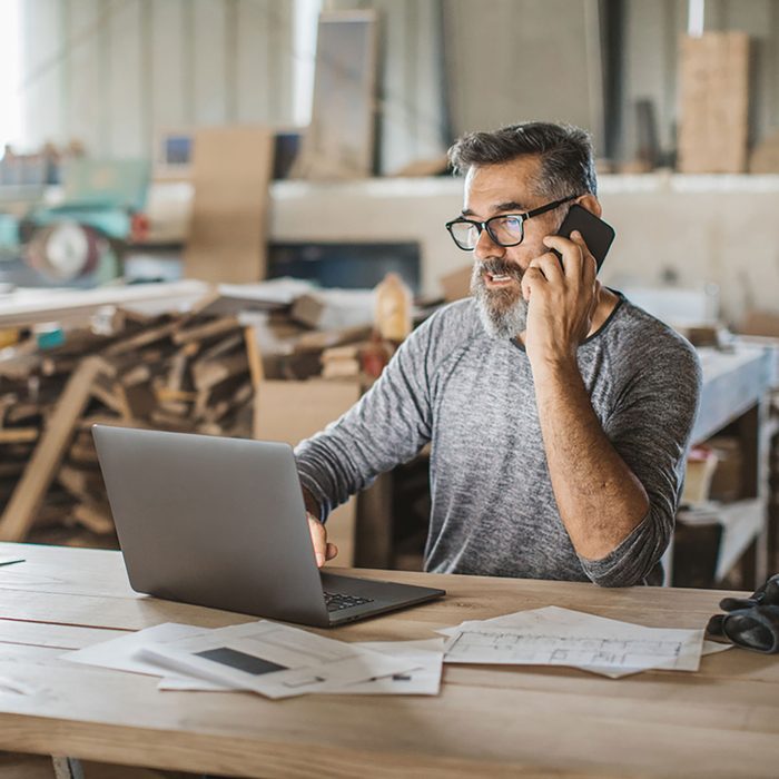 A workshop owner on the phone at his laptop