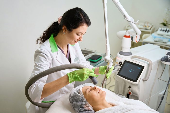 An aesthetician treating a client with a laser device