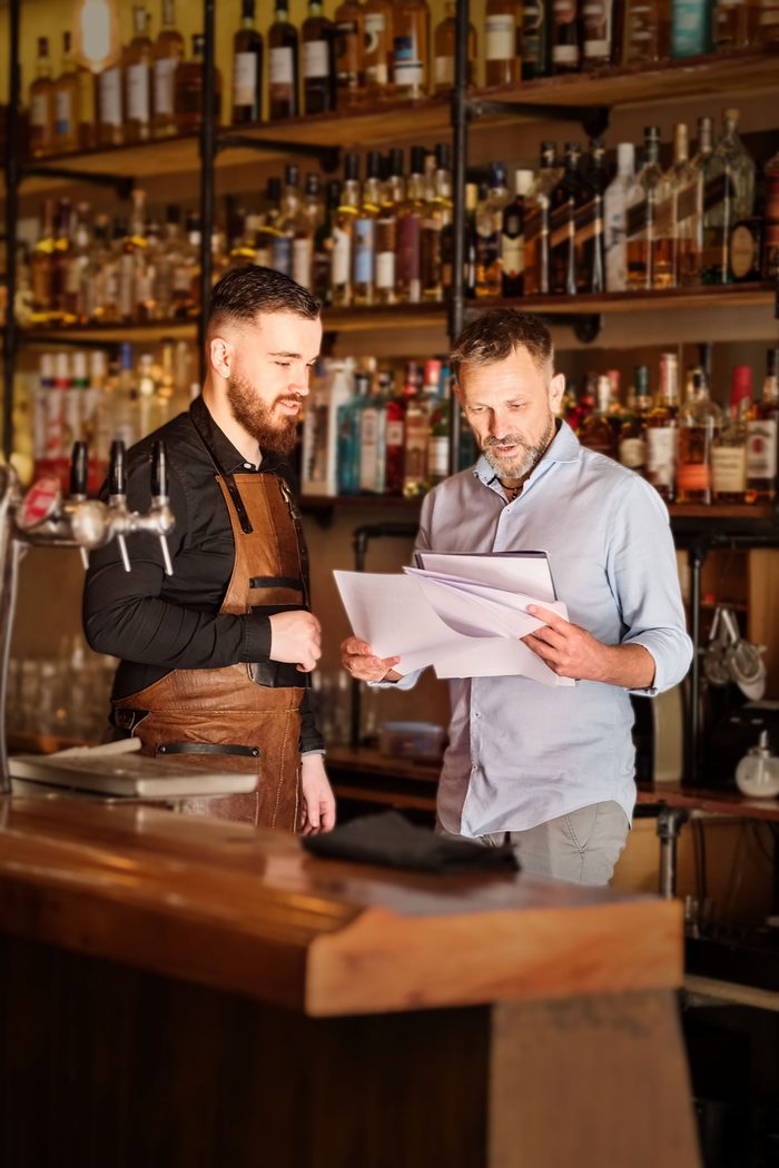 Business merchant cash advance: two bar owners going over paperwork behind the bar